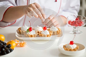 Close up of female confectioner hands topping custard tarts