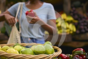 Close Up Of Female Customer At Market Stall Choosing Red Bell Pepper With Lemons In Foreground