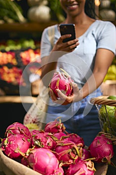 Close Up Of Female Customer At Market Stall Taking Photo Of Fresh Dragon Fruit On Mobile Phone