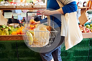 Close Up Of Female Customer With Shopping Basket Buying Fresh Produce In Organic Farm Shop