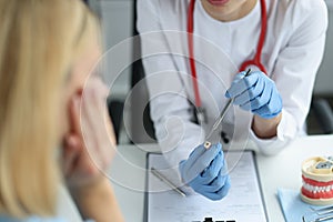 Female dentist showing patient tooth with hole inside and caries