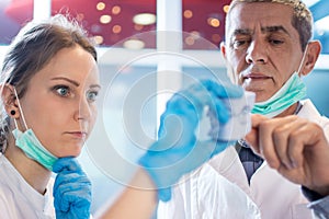 Close up of female dentist showing a plaster model to her older colleague in dental office