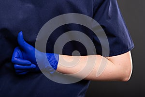 Close-up of female dentist wearing scrubs showing like gesture