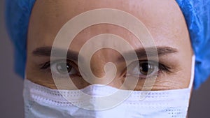 Close up of female doctor face with medical mask looking seriously and nodding with regrets. Surgeon woman head denies