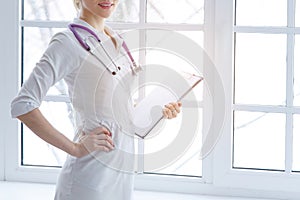 Close-up of a female doctor while filling up medical application form with sunlight