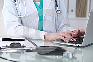 Close-up of female doctor hands typing on laptop computer. Physician at work. Medicine, healthcare and help concept