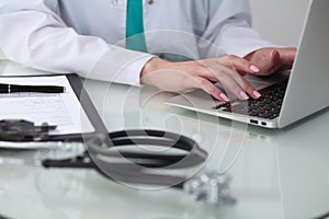 Close-up of female doctor hands typing on laptop computer. Physician at work. Medicine, healthcare and help concept