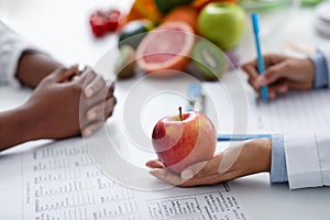 Close up of female doctor holding big fresh red apple