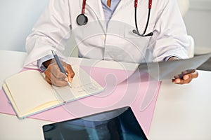 Close-up of female doctor making notes at table with x-ray image