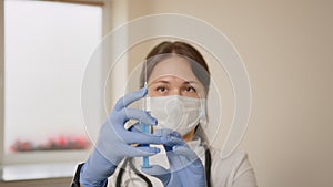 Close-up of a female doctor in a medical mask holding an insulin syringe, she releases air from the syringe. Vaccination