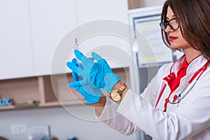 Close up of a female doctor  nurse  holding a syringe while standing in a medical office