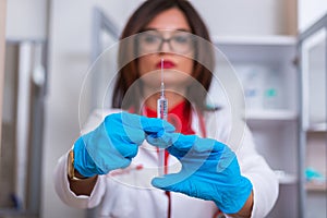 Close up of a female doctor  nurse  holding a syringe while standing in a medical office