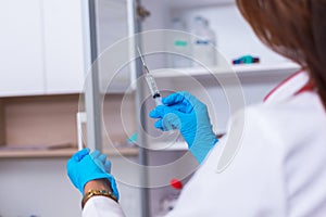 Close up of a female doctor  nurse  holding a syringe while standing in a medical office