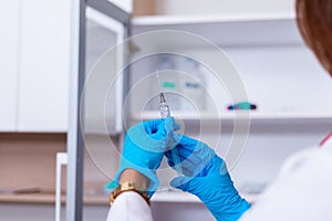 Close up of a female doctor  nurse  holding a syringe while standing in a medical office