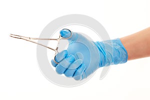 Close up of female doctor's hand in blue sterilized surgical glove with forceps against white