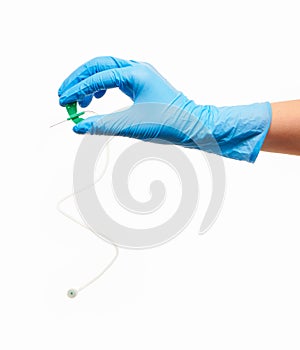 Close up of female doctor's hand in blue sterilized surgical glove with green plastic catheter against white