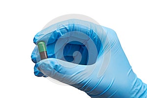 Close up of female doctor's hand in blue sterilized surgical glove holding green and black capsule