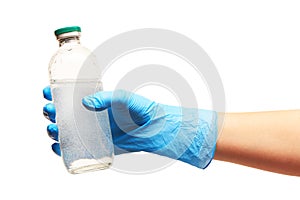 Close up of female doctor's hand in blue sterilized surgical glove holding transparent white glass bottle for medicines with a dru