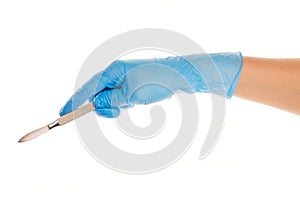 Close up of female doctor's hand in blue sterilized surgical glove with scalpel against white