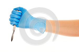 Close up of female doctor's hand in blue sterilized surgical glove with scalpel against white