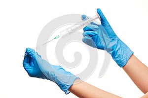 Close up of female doctor's hands in blue sterilized surgical gloves with plastic medical syringe against white