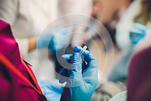 Close up of female doctor`s hands putting on blue sterilized surgical gloves in the office.