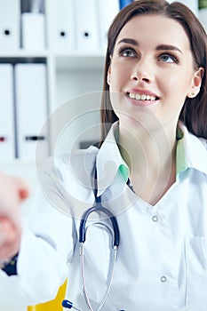 Close up of female doctor shaking hands with her patient. Medicine and trust concept