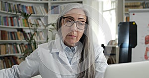 Close up of female doctor showing x ray photo while having online medical consultation in office. Mature woman in