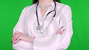 Close-up, female doctor, surgeon, dressed in a white medical uniform and with a stethoscope, standing with crossed hands