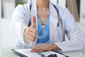 Close up of female doctor thumbs up. Happy cheerful smiling brunette physician ready to examine patient. Medicine