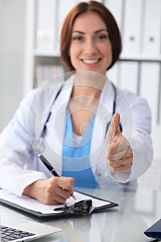 Close up of female doctor thumbs up. Happy cheerful smiling brunette physician ready to examine patient. Medicine