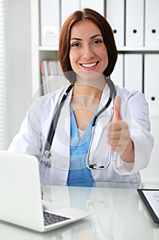 Close up of female doctor thumbs up. Happy cheerful smiling brunette physician ready to examine patient. Medicine