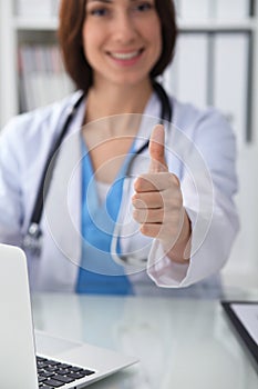 Close up of female doctor thumbs up. Happy cheerful smiling brunette physician ready to examine patient. Medicine