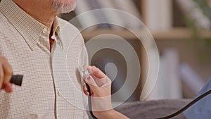 Close up Female doctor use stethoscope to examine elderly patient heartbeat. Caring female doctor use tools examine mature male