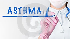 Close up female doctor writing word ASTHMA with marker. Medical concept