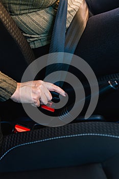 Close-up of female driver's hand adjusting seat belt inside her car.