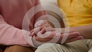 Close-up female elderly hands holding hand of child unrecognizable loving tender grandmother support grandson kid boy