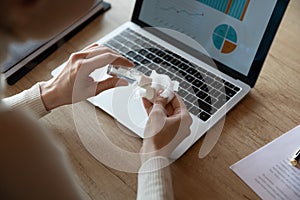 Close up of female employee cleanse computer with sanitizer