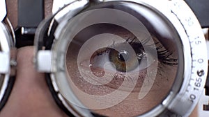 Close-up female eye in optical trial frame, lens selection, vision checking