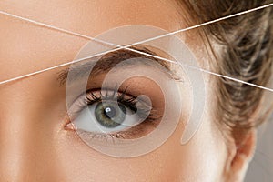 Eyebrow threading - epilation procedure for brow shape correction photo