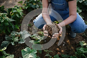 Close up of female famer hands holding soil outdoors at community farm.