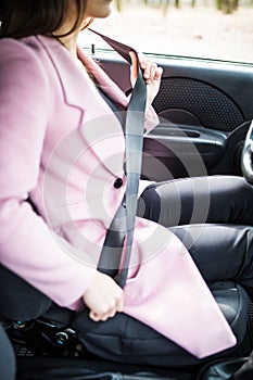 Close up of female fastening safety belt in car before drive
