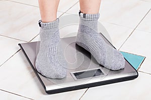 Close up female feet on digital weighting scale.