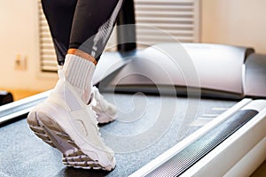 Close up female feet on modern treadmill in gym