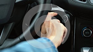 Close up of female finger pressing an engine start stop button in car