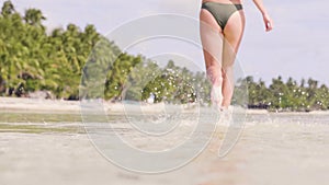 Close up female foot running on sea water at tropical beach. Beautiful woman in bikini running on water at ocean shore