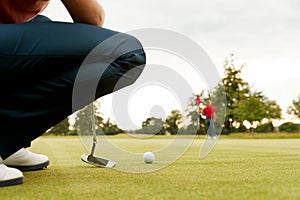 Close Up Of Female Golfer Lining Up Shot On Putting Green As Man Tends Flag