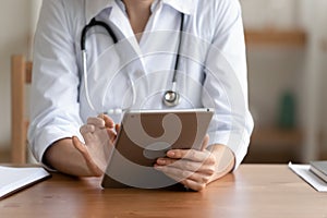 Close up of female GP use modern tablet in clinic