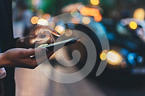 Close up female hand calling taxi with a smartphone app., businesswoman using cellphone with yellow taxi background night street