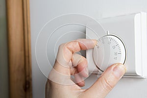 Close Up Of Female Hand On Central Heating Thermostat photo